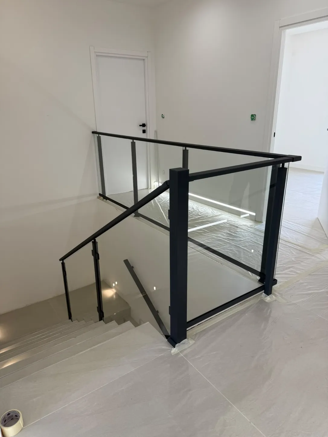 garde-corps intérieur verre transparent et cadre aluminium noir autour d’une trémie d’escalier